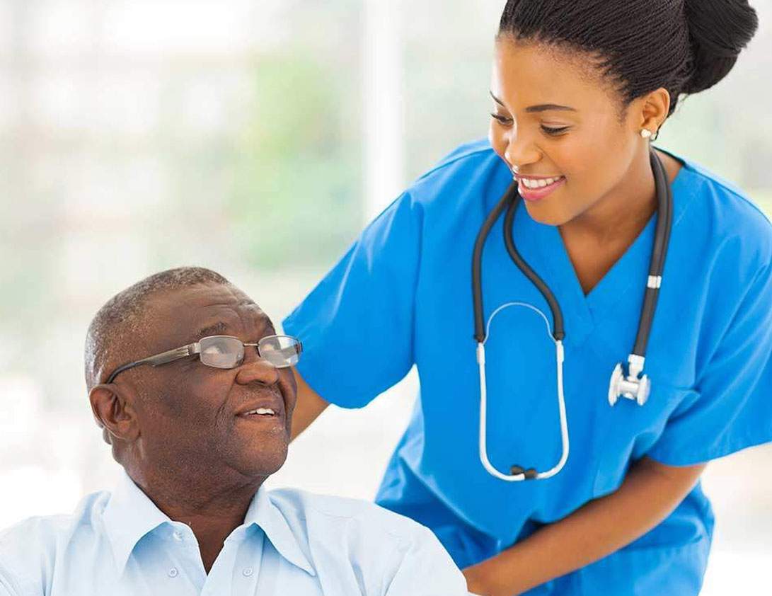 A nurse wearing a stethoscope leans over a client