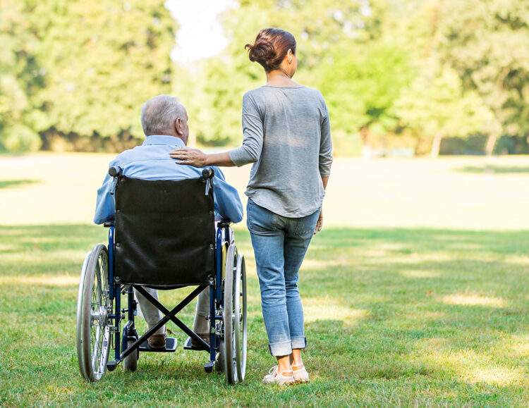 A caregiver stands next to a client in a wheelchair