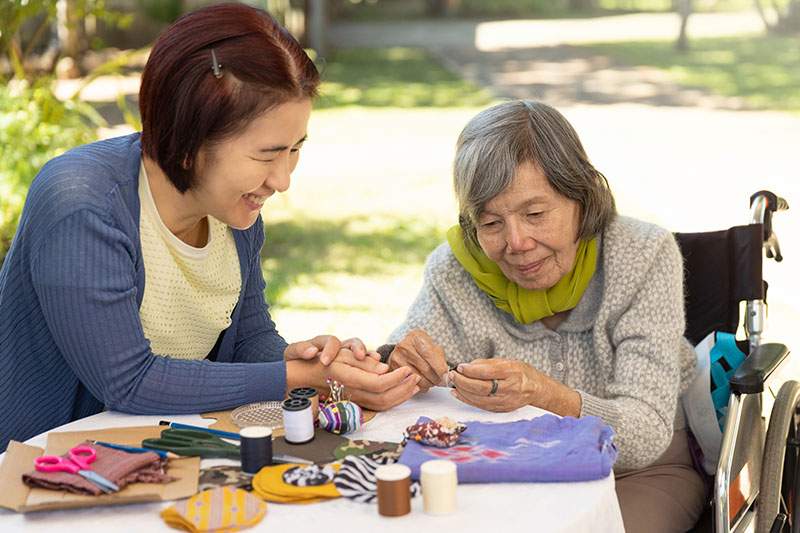 woman doing an activity outside with elderly woman in wheelchair