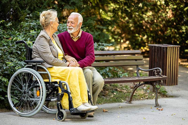 man on park bench and woman in wheelchair