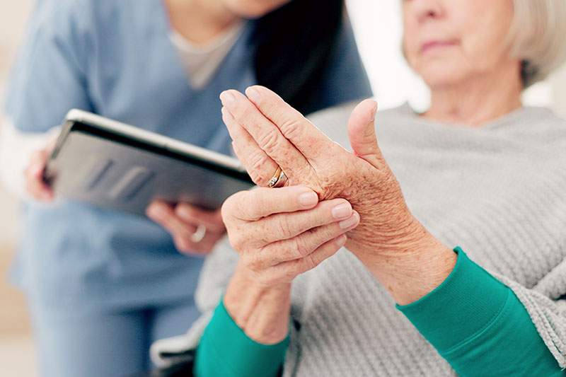 woman showing her hands to an aid with a tablet